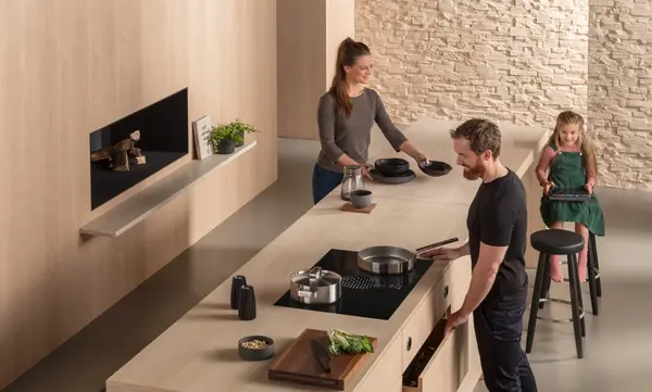 Moderne offene Küche mit Familie beim Kochen und Vorbereiten am Kochfeld und Kücheninsel.