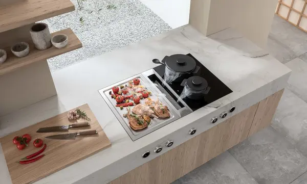 Moderne Küche mit Kochfeld, Dunstabzug und frischen Zutaten auf Arbeitsplatte.