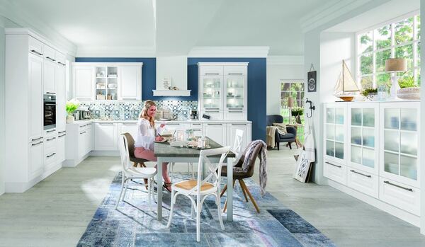 Helle, moderne Landhausküche mit weißen Möbeln, maritimer Deko und Essbereich.