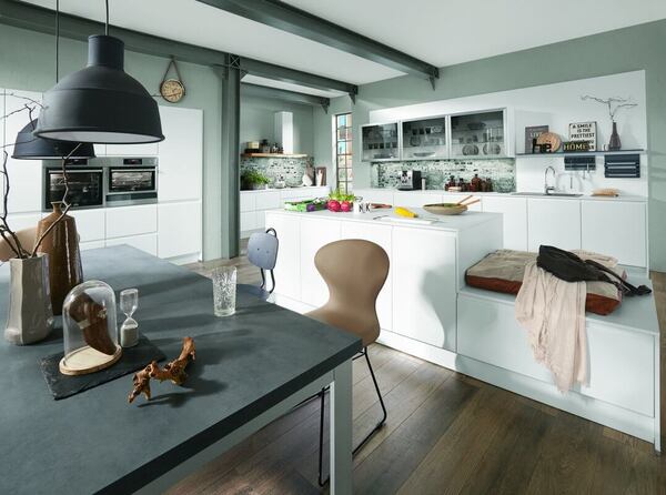 Moderne, helle Einbauküche mit Kochinsel, Sitzbank, Esstisch und stilvoller Dekoration.