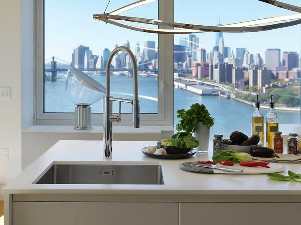 Moderne Küche mit Gemüse, Kräutern und Blick auf die Skyline und eine große Brücke.