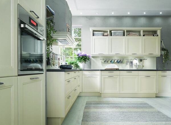 Moderne helle Einbauküche mit viel Stauraum, Elektrogeräten und großen Fenstern.