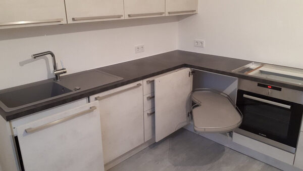 Moderne Einbauküche mit Eckschrank, Auszug, Spüle, Backofen und hellen Fronten.