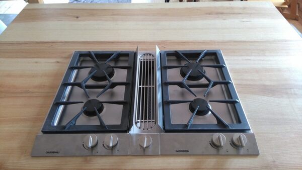 Gaskochfeld mit vier Kochzonen und Abluftsystem von Gaggenau auf Holzarbeitsplatte.