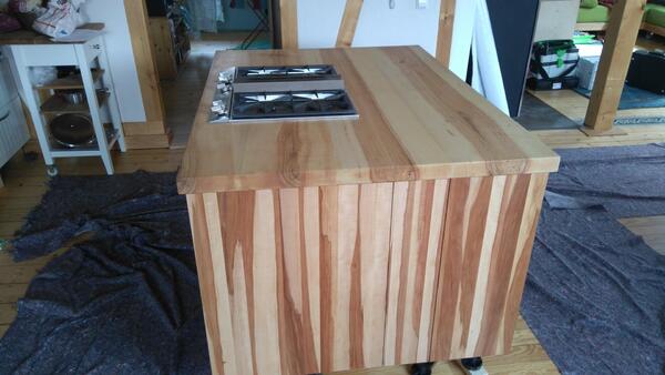 Kücheninsel aus Massivholz mit zwei Gaskochfeldern in modernem, offenem Wohnraum.