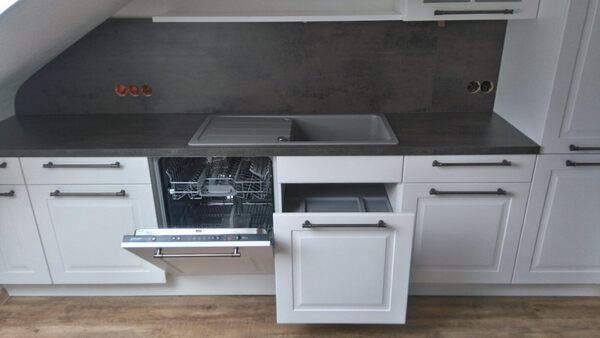 Moderne Einbauküche mit Spülmaschine, Spüle und offenen Schubladen unter Arbeitsplatte.