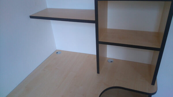 Eckschreibtisch aus hellem Holz mit Regal und Kabeldurchlässen für Büro oder Homeoffice.