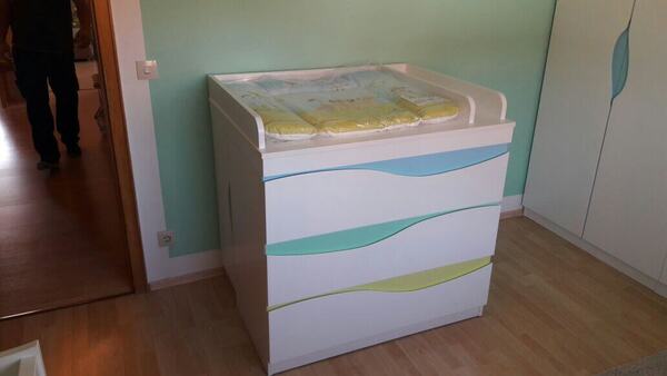 Moderne Wickelkommode mit bunten Schubladen in einem hellen, freundlich eingerichteten Kinderzimmer.